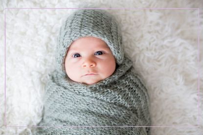 Newborn baby wrapped in a wool blanket wearing a woolen hat