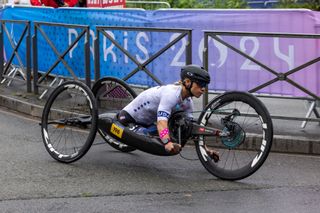 Oksana Masters competes for Team USA during the Paris Paralympics in her hand cycle with Zipp wheels. She is wearing a black aero road helmet and white Team USA jersey.