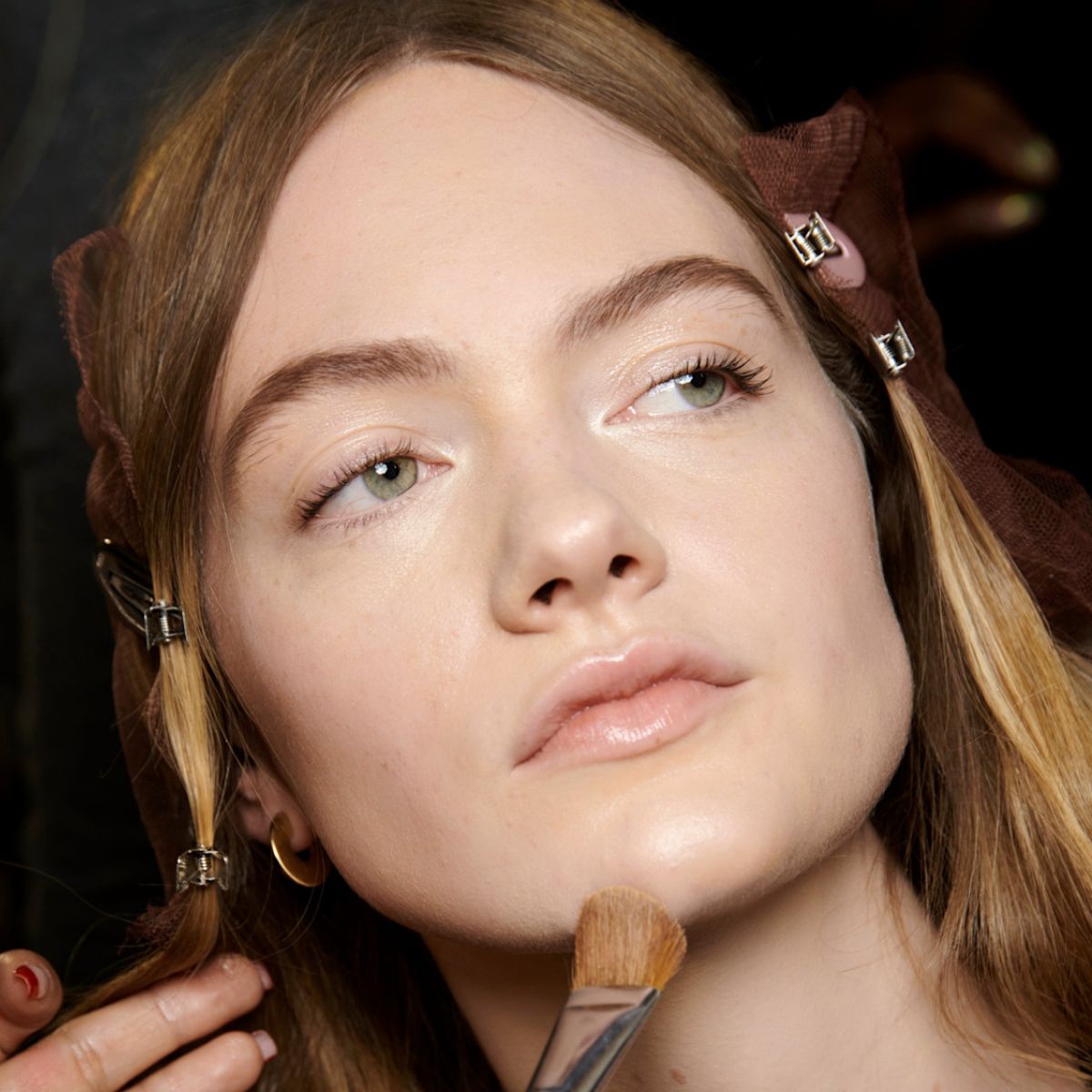 model backstage having foundation applied to her skin
