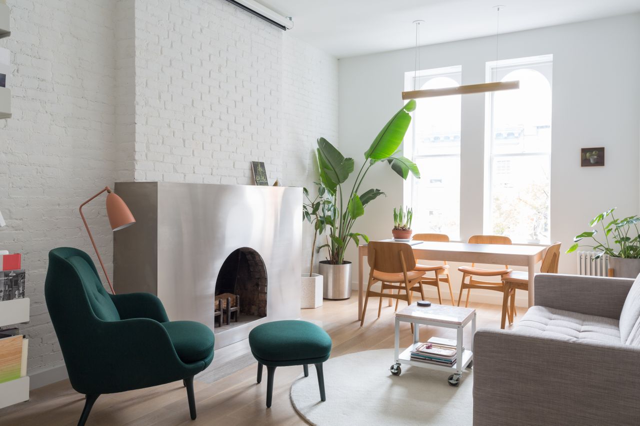 living room with white walls, grey sofa and stainless steel wrapped fireplace