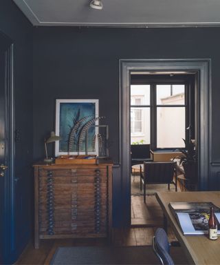 Dining room painted black with an antique brown dresser and colorful artwork