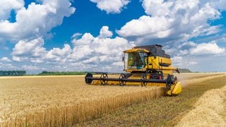 Great combine harvester working at the field. Agricultural machine on the blue sky.