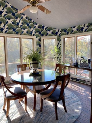 Bright sunroom with brick flooring, dining room table and patterned wallpaper