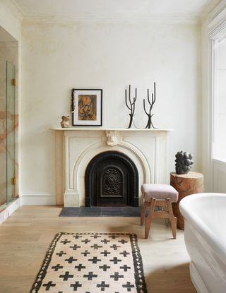 An example of bathroom art ideas showing a neutral bathroom with a fireplace and a monochrome rug