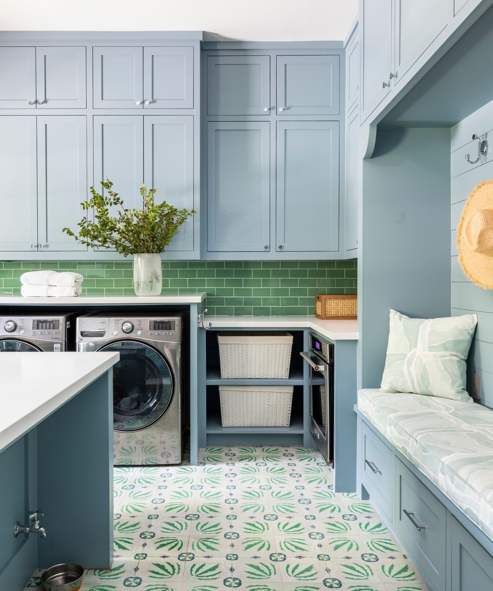 Laundry room with blue fitted cabinets, island, patterned floor and green splashback tiles