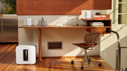 Sonos Sub (Gen 3) Wireless Subwoofer in white next to wooden desk in home office area