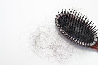 Hairball next to hair brush.