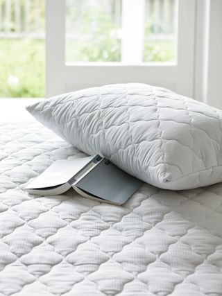 mattress and pillow protector on a bed with a book