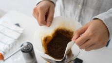 A man holding the coffee filter full of spent coffee grounds. Coffee grounds can be recycled. The spent coffee grounds can be used to produce useful things.