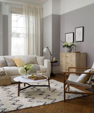 grey living room with cream sofa round coffee table and large berber rug