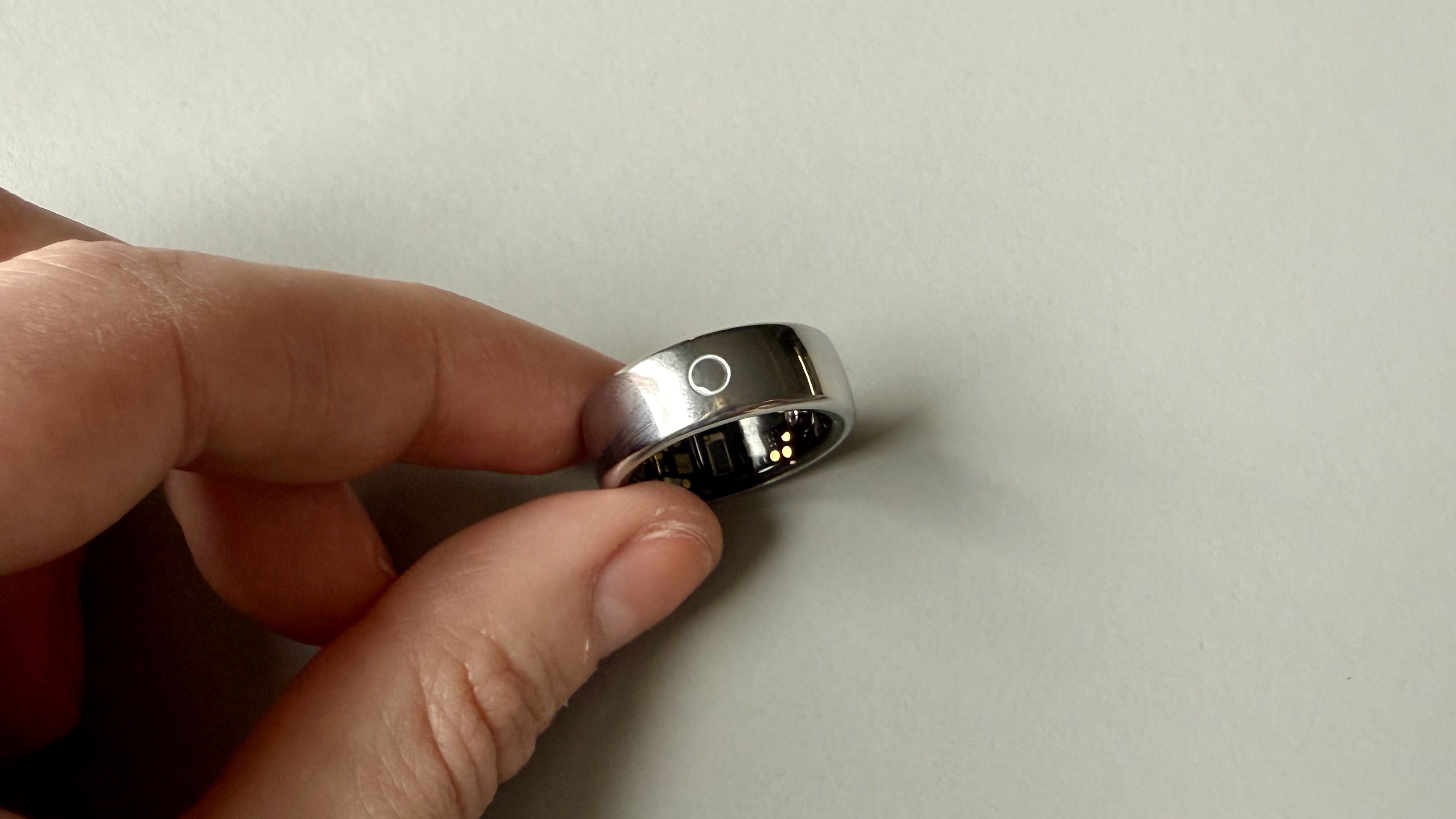 Becca holding the circular ring 2 smart ring against a grey surface