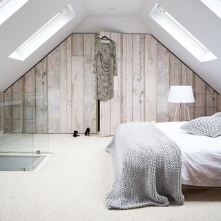 attic bedroom with wood panelled cupboard and bedside lamp