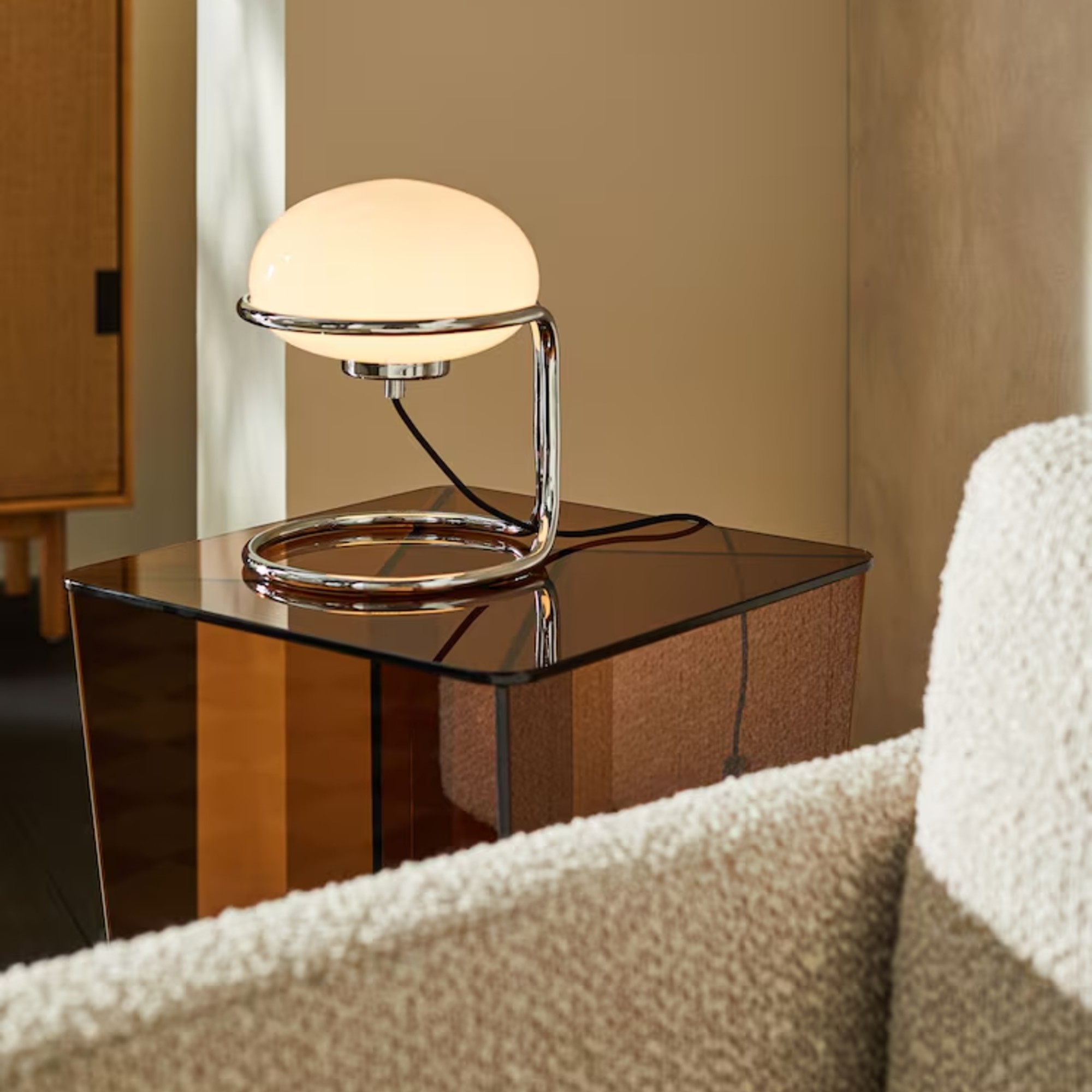MADE's Piper Table Lamp in Chrome on an amber glass side table in a living room