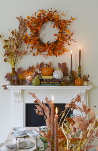 A mantel with a fall wreath place above