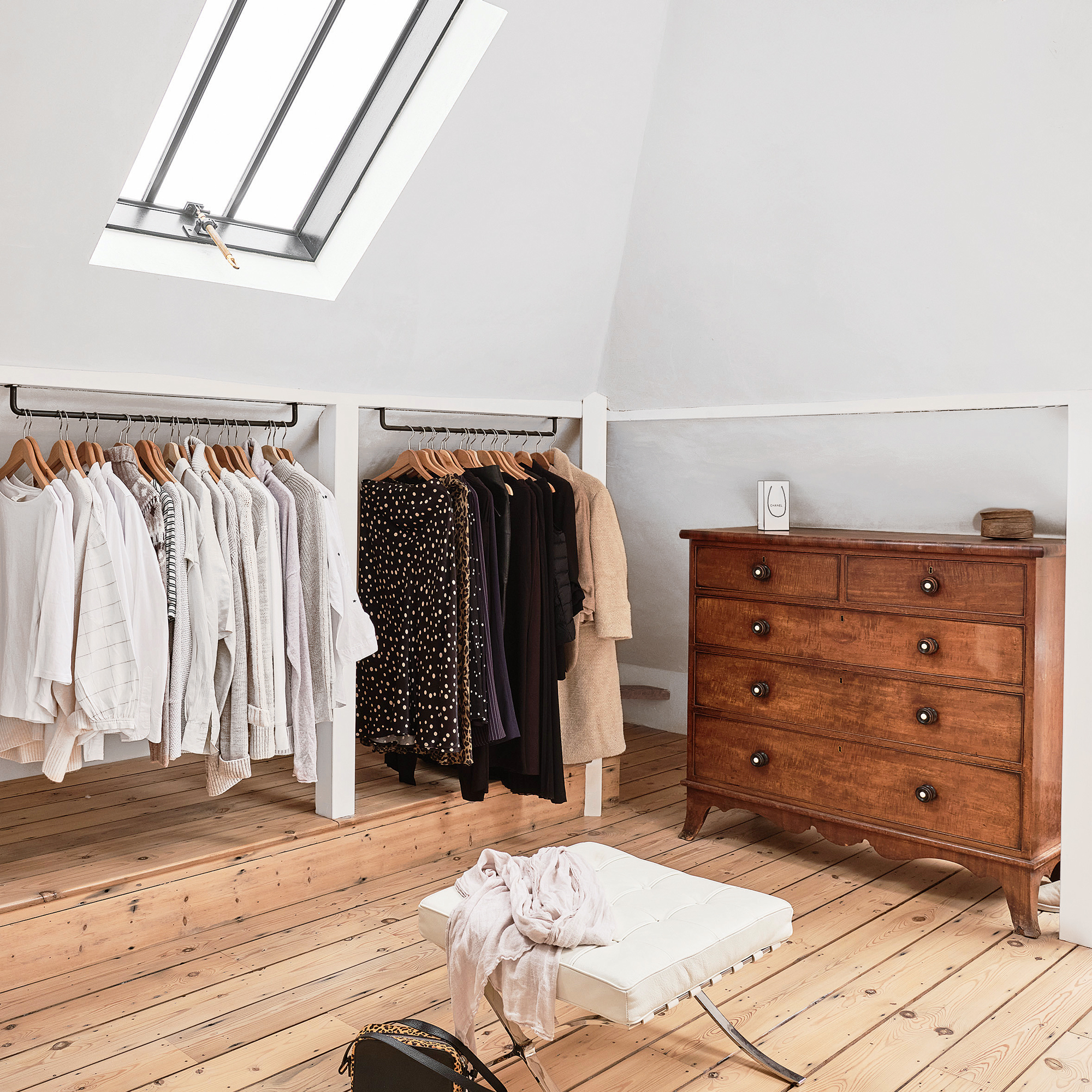 a bedroom with eaves hung clothes rails acting as an open wardrobe