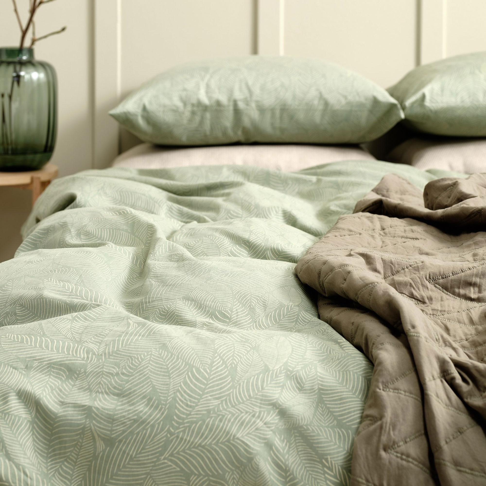 Green linen bedding with a dark green throw on top