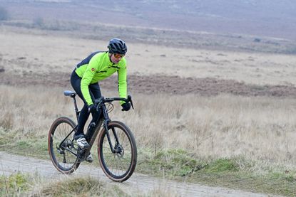 man riding a black gravel bike wearing a yellow top and black helmet