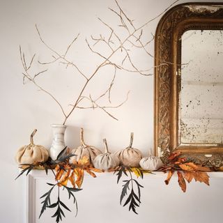 small fabric pumpkins on a shelf or mantelpiece beside a mirror