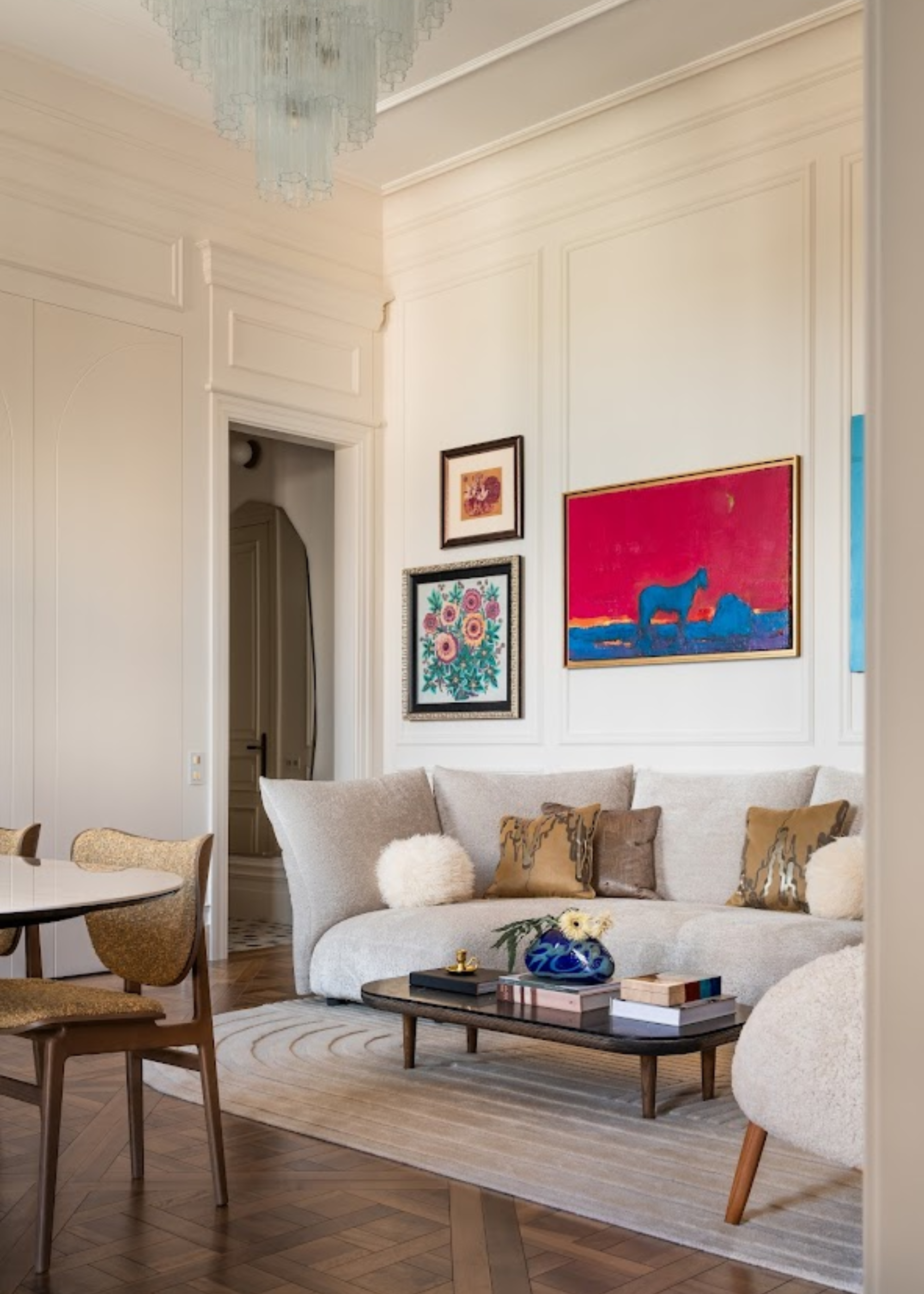 A bright living room with a sofa and a gallery wall of gold framed art above