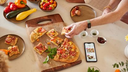 person reaching for a slice of pizza wearing the Amazon Halo View fitness tracker