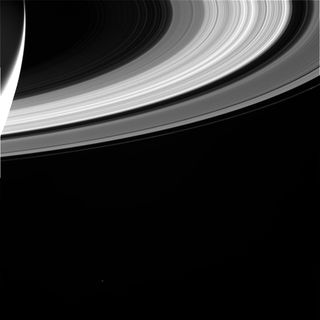 Saturn's rings reach across the photo, and the bottom of the gas planet itself