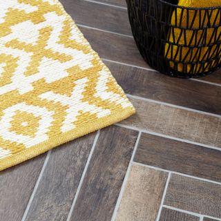 bathroom with wooden flooring with bath mat and mustard towel in black basket