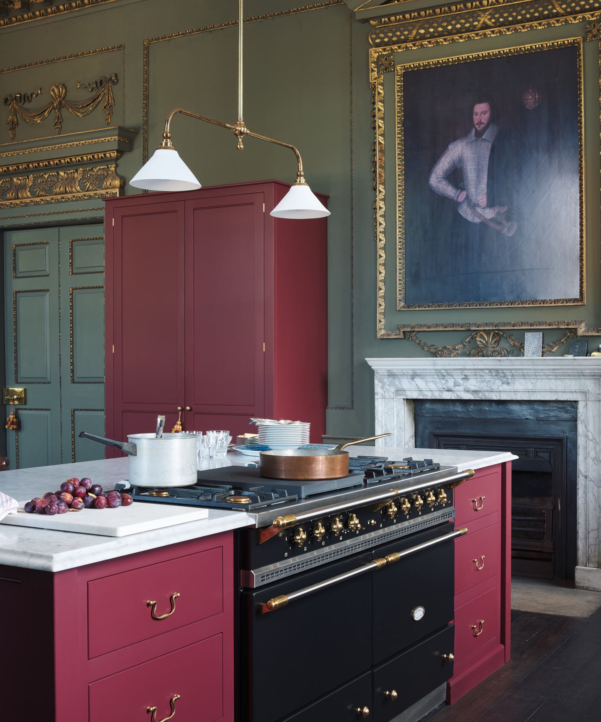 A stately home kitchen with green walls, red cabinetry, and marble countertops