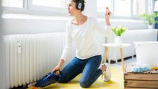 Woman at home wearing headphones hoovering the floor 
