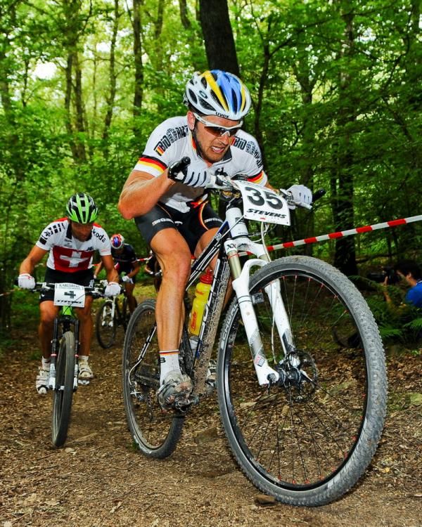 Karl Platt (Germany) leads Ralph Naef (Switzerland) uphill through a forested section.