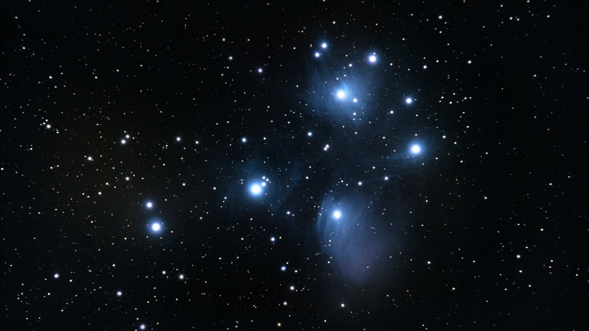 A series of bright blue and white stars shine in a deep space image