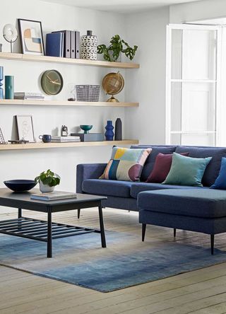neutral living room with floating walls shelves and a navy blue sofa