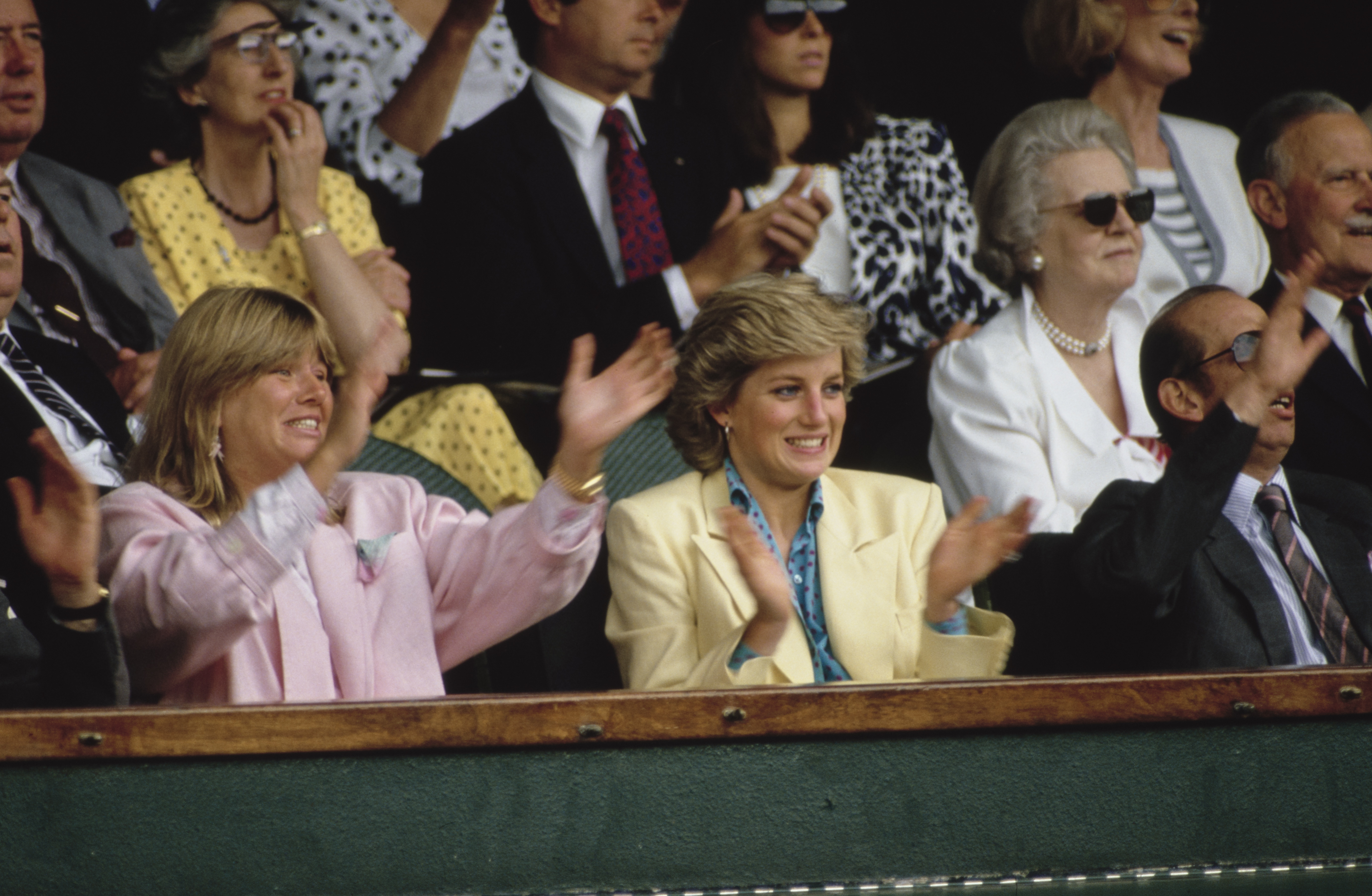 Princess Diana clapping in a yellow blazer at Wimbledon