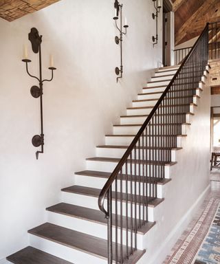 stairs with rustic iron wall sconces