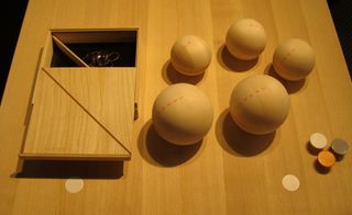 Storage set, by Nomess Copenhagen. A wooden box with lid slid open next to four wooden balls.