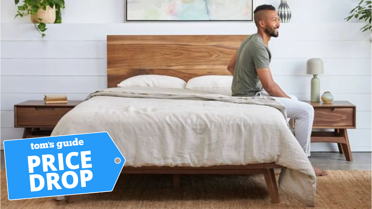 Man sitting on the edge of an avocado mattress that has avocado bedding on it with a Price drop label on top of the image