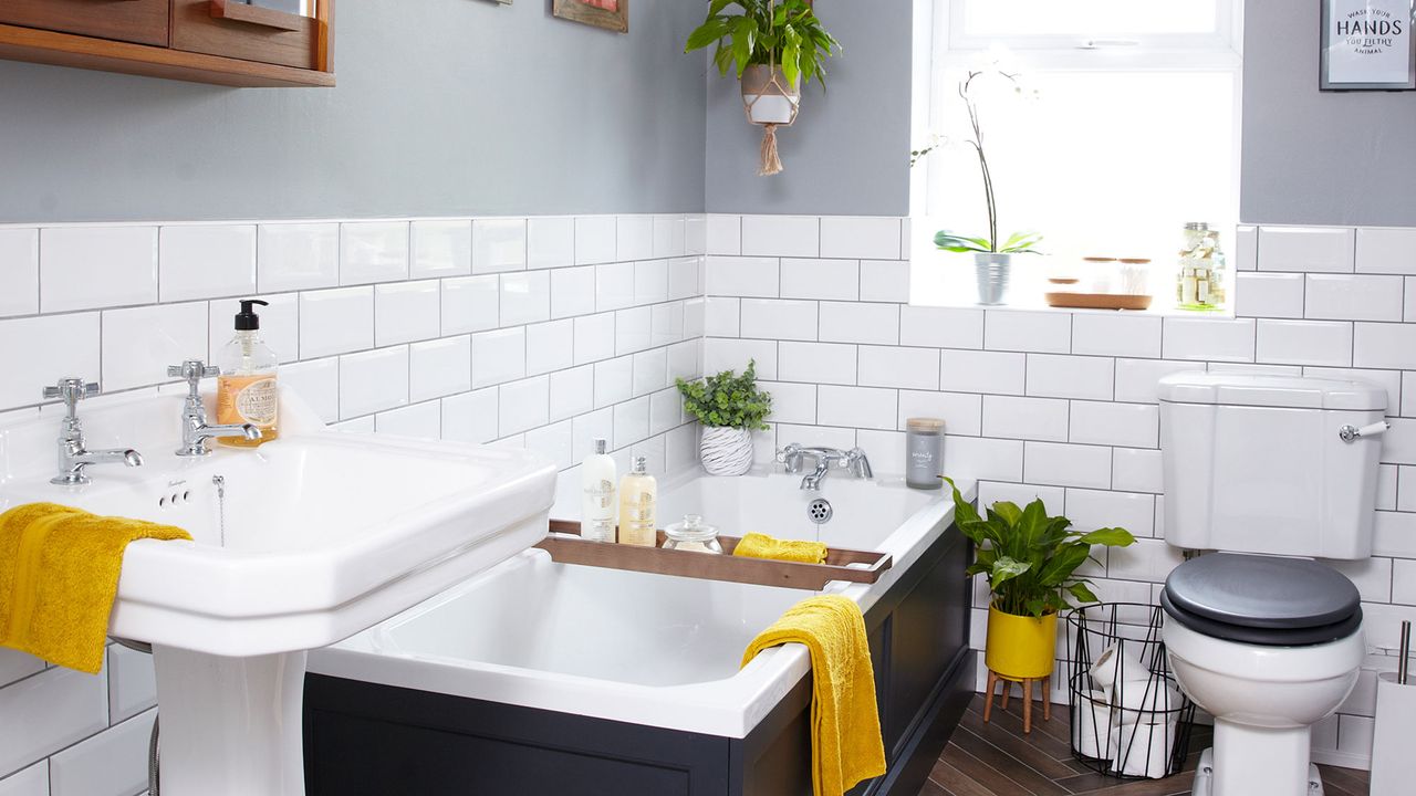 White and grey bathroom with yellow towels and bathmat