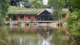 single storey timber frame house with timber cladding, green roof and pitched gable end