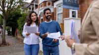 Real estate agent handling the blueprints of a house for sale to a couple