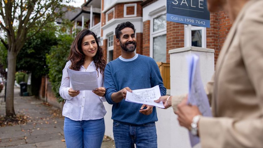 Real estate agent handling the blueprints of a house for sale to a couple