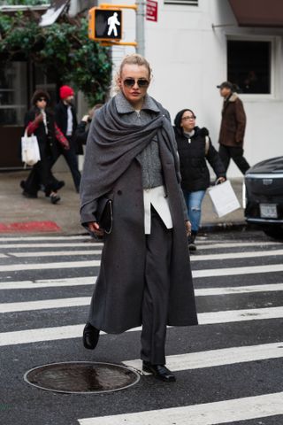 A woman at fashion week in a gray coat and shawl