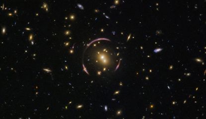 Hubble captured this image of the universe's many galaxies, with an Einstein ring to boot. When the light from distant galaxies warps around an extremely large mass, like a galaxy cluster, it creates this elegant ring.