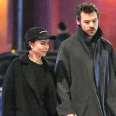 Zoe Kravitz and Harry Styles wearing black coats and loafers and walking in NYC