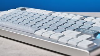 The NuPhy Nos75 mechanical keyboard on a stone surface with a blue background