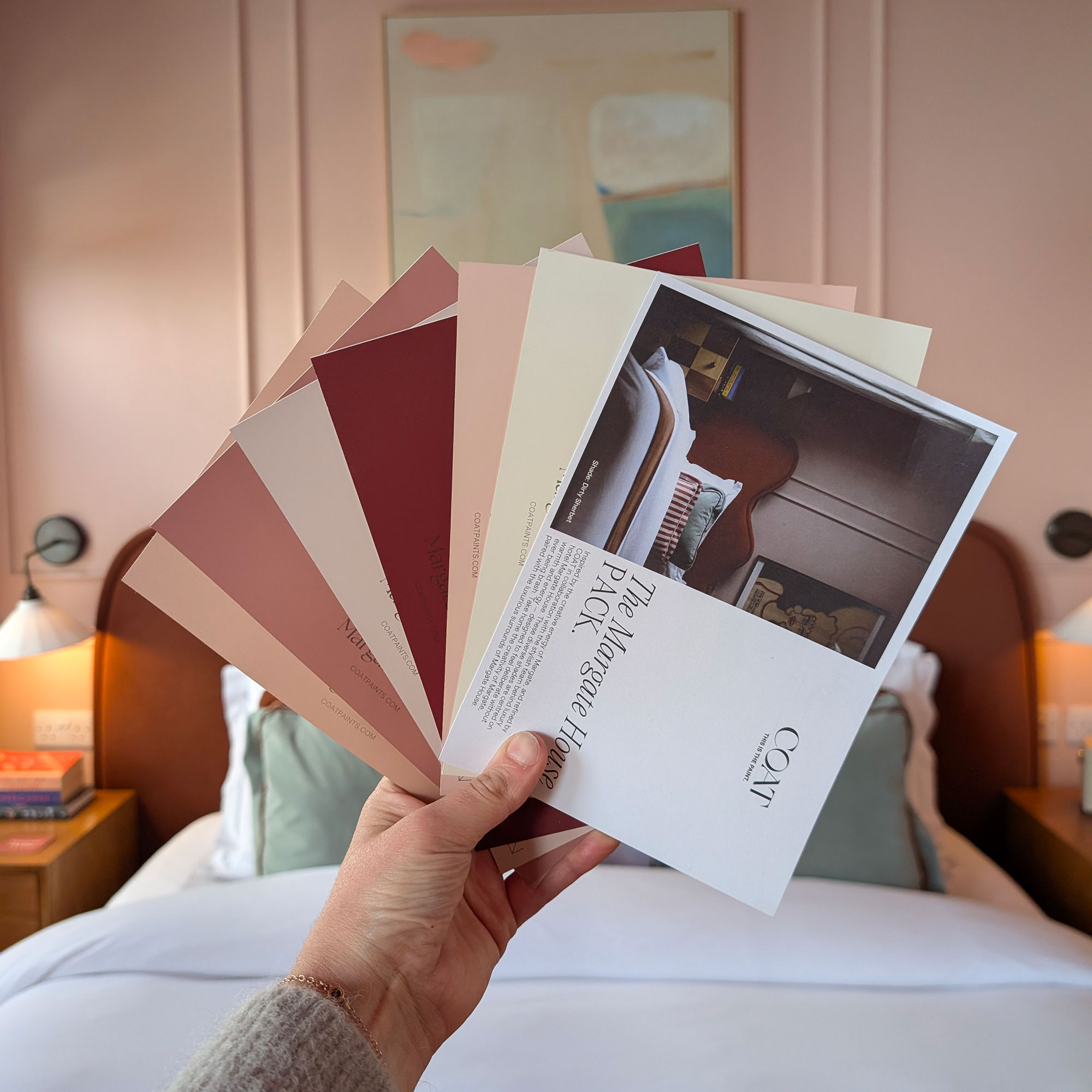 Person holding up selection of pink based paint samples in fan shape