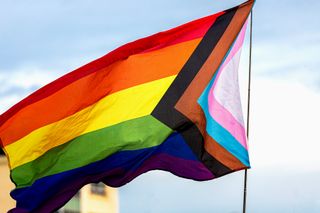 LGBTQ+ ally— Rainbow flag showing support for the LGBT community with people at the pride event