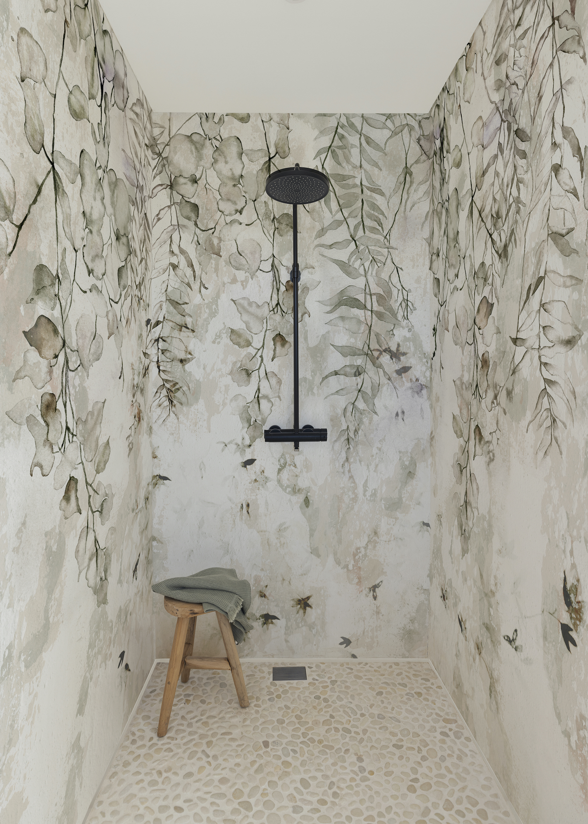 bathroom with pebble floor and leafy walls and a shower in the middle of the the space. There is also a stall on the side of the shower with a towel on top