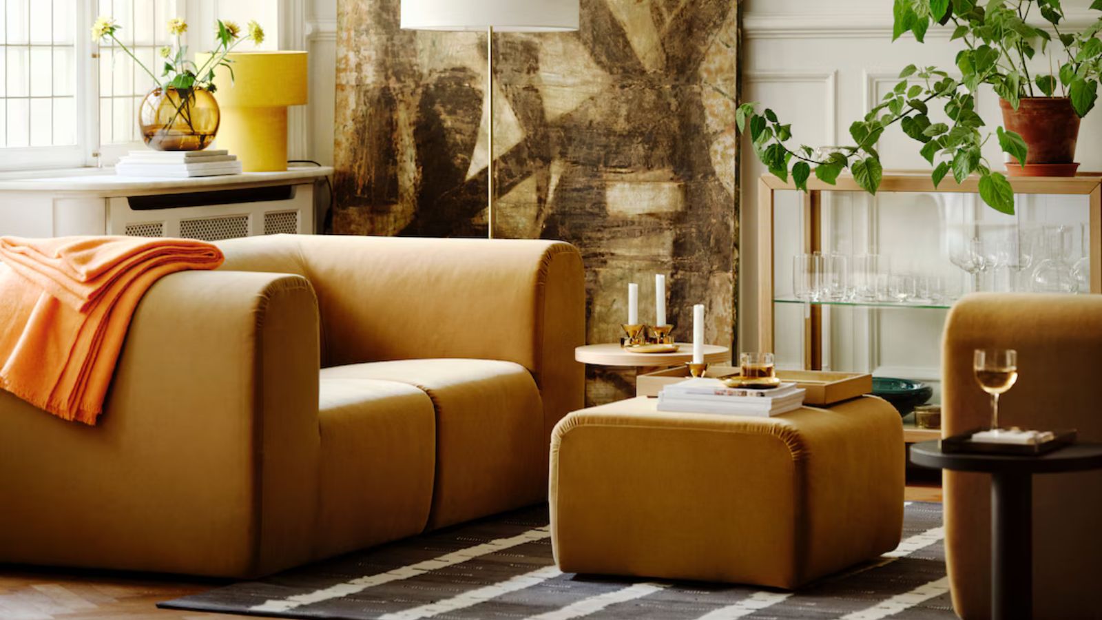 IKEA living room with chunky mustard armchair and matching footstool with striped gray and white rug underneath