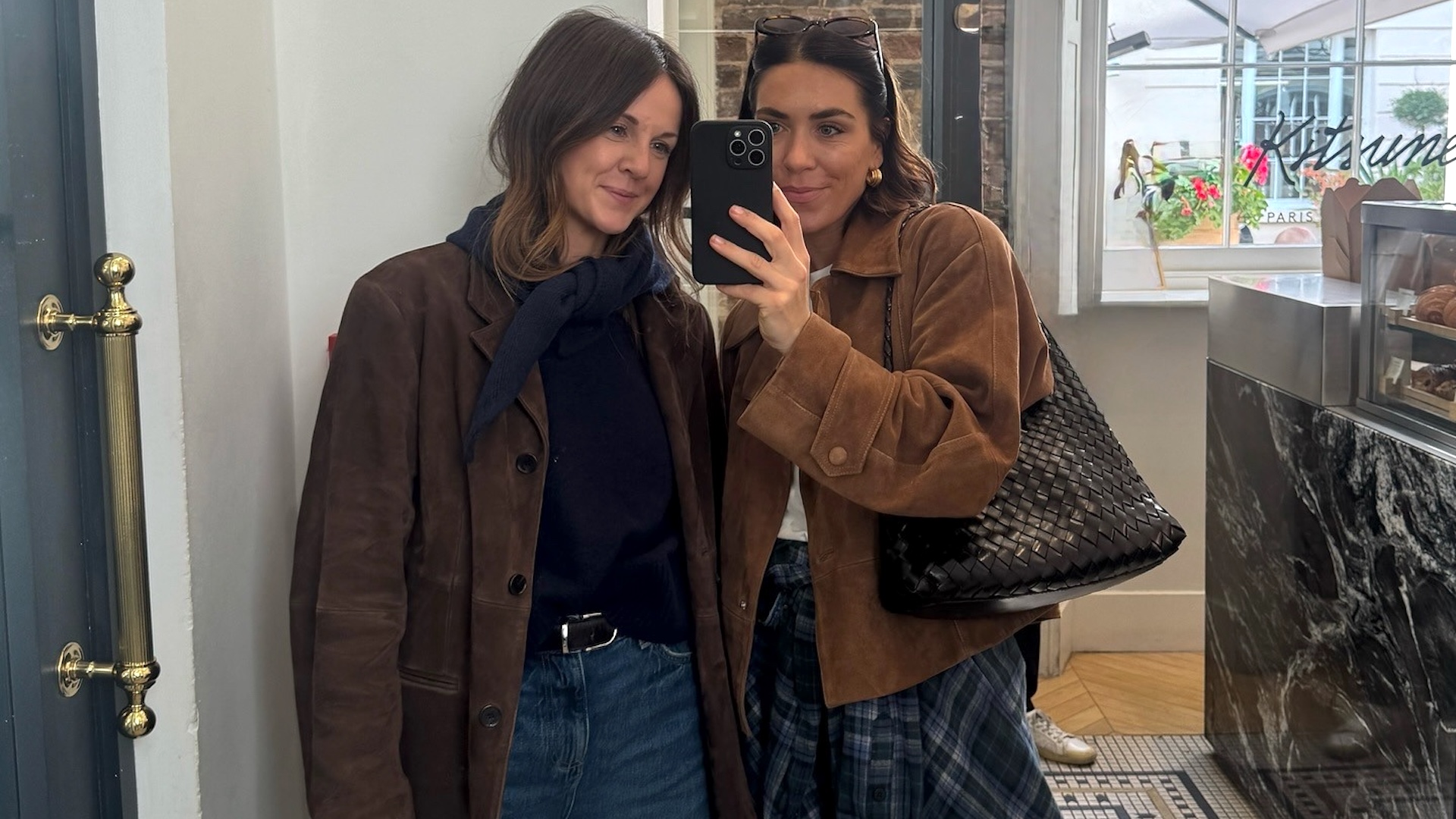 British style influencers Kim Turkington and Jessica Skye pose for a mirror selfie at Cafe Kitsune in London wearing chic outfit ideas with brown suede jackets and jeans.