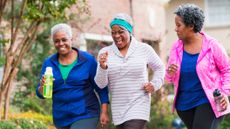 Three women in sportswear walking and smiling, two carry water bottles