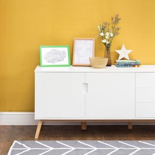 yellow wall with white cabinet and flower on vase